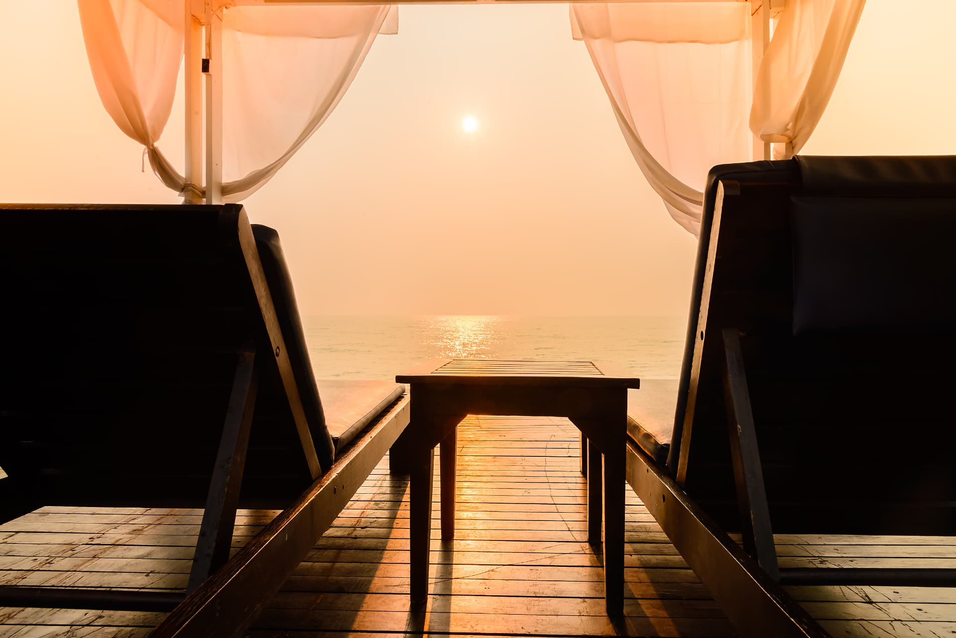 Sunlit private deck with loungers overlooking a calm golden sea